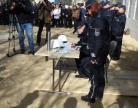 Komendant Wojewódzki Policji w Białymstoku podpisuje akt erekcyjny. W tle policjanci uczestniczący w uroczystości i widzowie.