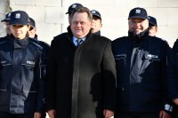 Wiceminister Spraw Wewnętrznych i Administracji pozuje do zdjęcia na tle policjantów