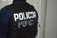 Fotografia przedstawia sylwetkę funkcjonariusza policji w kamizelce taktycznej z napisem &quot;Policja&quot;