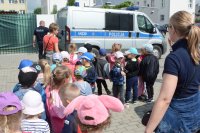 Fotografia przedstawia dzieci z Przedszkola  w Ciechanowcu na spotkaniu  z wysokomazowieckimi policjantami na placu  Komendy Powiatowej Policji- dzieci oglądają radiowozy