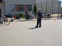Fotografia przedstawia funkcjonariuszy Wydziału Ruchu Drogowego przeprowadzających  testy praktyczne z uczniami na kartę rowerową