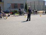 Fotografia przedstawia funkcjonariuszy Wydziału Ruchu Drogowego przeprowadzających  testy praktyczne z uczniami na kartę rowerową
