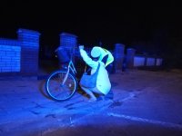 Obraz przedstawia policjanta wraz z rowerzystą, który odbiera odblask na jednoślad