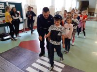 Obraz przedstawia policjanta wydziału ruchu drogowego z dziećmi na spotkaniu w Czyżewie
