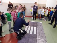 Obraz przedstawia policjanta wydziału ruchu drogowego  z dziećmi na spotkaniu w Czyżewie