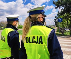 Obraz przedstawia policjantów wydziału ruchu drogowego znajdujących się przed przejściem dla pieszych