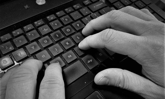 Obraz przedstawia dłonie i klawiaturę komputera
