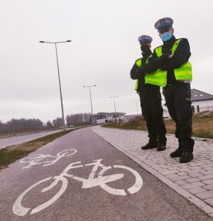 Obraz przedstawia policjantów stojących przy ścieżce rowerowej