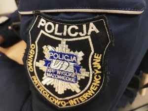 Obraz przedstawia ramię policjanta z naszywką z napisem Ogniwo Patrolowo - Interwencyjne Komendy Powiatowej Policji w Wysokiem Mazowieckiem