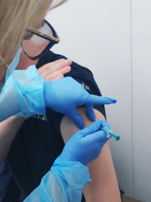 Obraz przedstawia ramię policjanta przyjmującego szczepienie