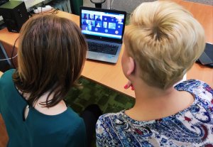 Obraz przedstawia dwie kobiety patrzące w laptop