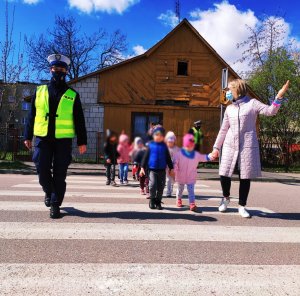 Obraz przedstawia policjantkę W tle dzieci przechodzące przez przejście dla pieszych