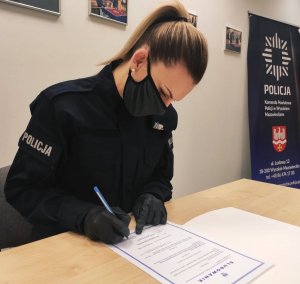 obraz przedstawia policjantkę podpisującą akt ślubowania