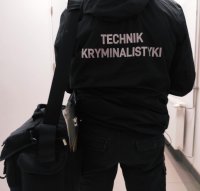 obraz przedstawia policjanta w kurtce z napisem Technik kryminalistyki