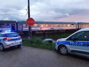 obraz przedstawia radiowozy policyjne, w tle pociąg