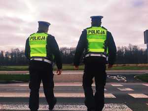 obraz przedstawia policjantów przechodzących przez przejście dla pieszych