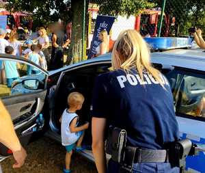obraz przedstawia policjantkę rozmawiającą z dziećmi na spotkaniu w Jabłoni Kościelnej, w tle radiowóz