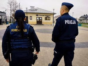obraz przedstawia policjanta oraz pracownika straży ochrony kolei w Szepietowie