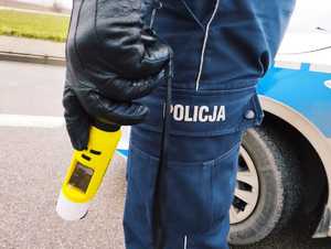 obraz przedstawia dłoń policjanta trzymającego urządzenie do badania stanu trzeźwości