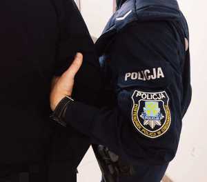 obraz przedstawia ramie policjanta oraz jego dłoń trzymającą ramię mężczyzny