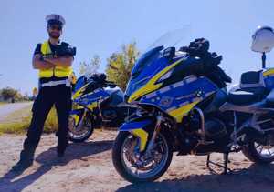 obraz przedstawia policjanta stojącego przy motocyklach