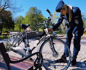 obraz przedstawia policjantkę stojącą przy rowerze