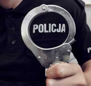 obraz przedstawia policjanta trzymającego kajdanki