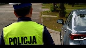 obraz przedstawia policjanta patrzącego na samochód