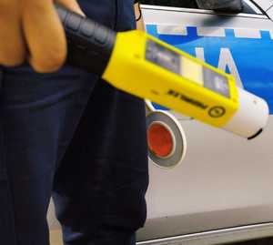 obraz przedstawia policjanta trzymającego urządzenie do badania stanu trzeźwości
