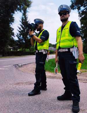 obraz przedstawia policjantów patrzących na drogę