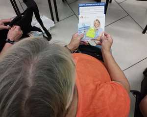 obraz przedstawia seniorkę trzymającą odblask i broszury profilaktyczne