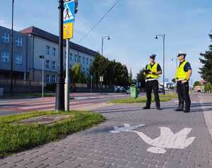 obraz przedstawia policjanta obserwującego drogę i patrzącego na znaki