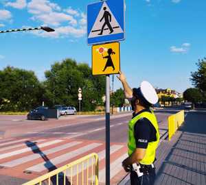 obraz przedstawia policjanta obserwującego drogę i patrzącego na znaki