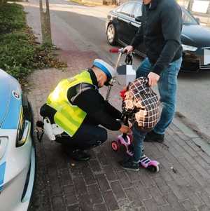 obraz przedstawia policjanta dającego odblask dziecku