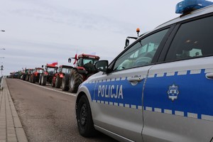 obraz przedstawia radiowóz na tle ciągników rolniczych