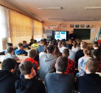 Obraz przedstawia dzielnicowego na spotkaniu z młodzieżą w Jabłonce Kościelnej