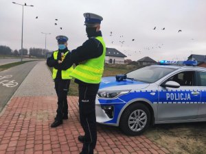 zdjęcie przedstawia dwóch policjantów ruchu drogowego stojących przy radiowozie policyjnym