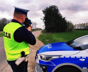 Fotografia przedstawia policjanta wysokomazowieckiej komendy wykonującego pomiar prędkości