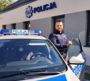 obraz przedstawia policjanta przy radiwozie