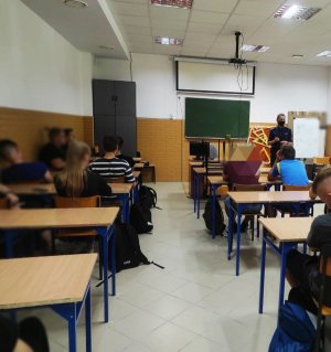 obraz przedstawia policjantkę oraz uczniów siedzących w ławkach