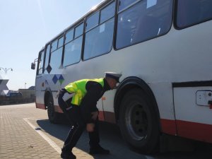 obraz przedstawia policjanta stojącego przy autokarze