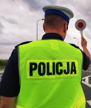 obraz przedstawia policjanta trzymającego w ręce tarcze do zatrzymywania pojazdów