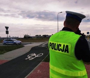 obraz przedstawia policjanta trzymającego w ręce urządzenie do pomiaru prędkości