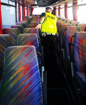 obraz przedstawia policjanta sprawdzającego autobus
