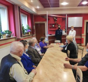 obraz przedstawia policjantkę i profilaktyk na spotkaniu z seniorami