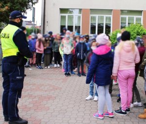 obraz przedstawia policjanta rozmawiającego z grupą dzieci