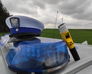 obraz przedstawia czapkę policjanta oraz urządzenie do pomiaru stanu trzeźwości na radiowozie