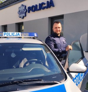 obraz przedstawia policjanta przy radiowozie