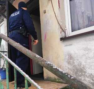 obraz przedstawia policjanta na tle murowanego budynku