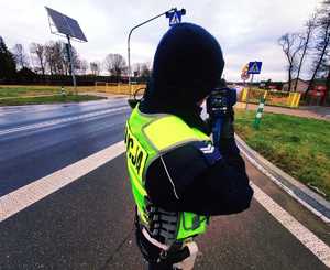 obraz przedstawia policjanta dokonującego pomiaru prędkości